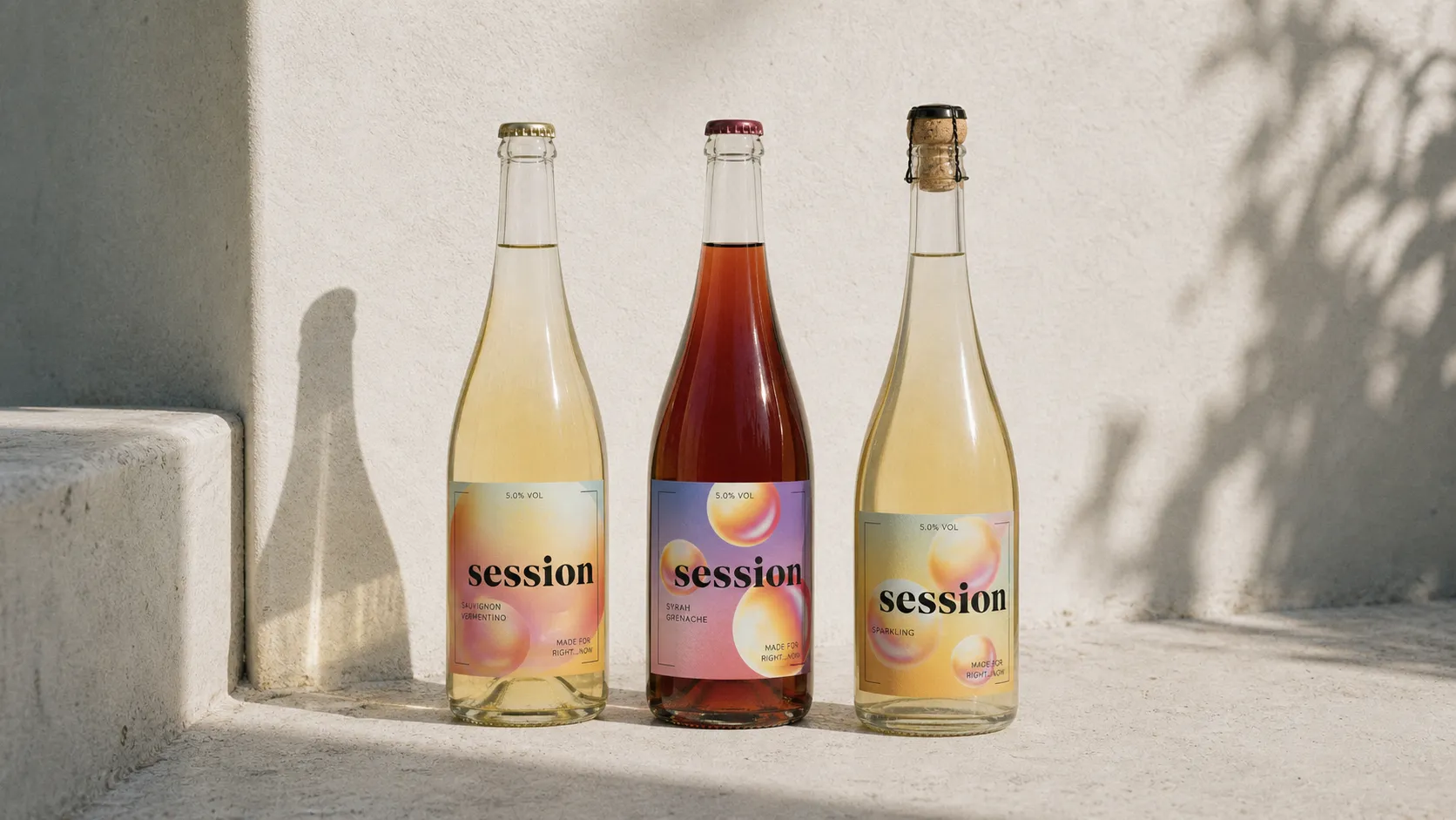 Three SESSION WINE bottles gathered on a pale stone surface in soft film light